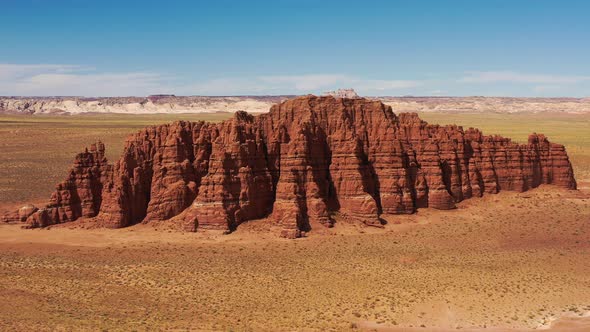 Elevated aerial panning around massive red rock formation in Utah desert, US