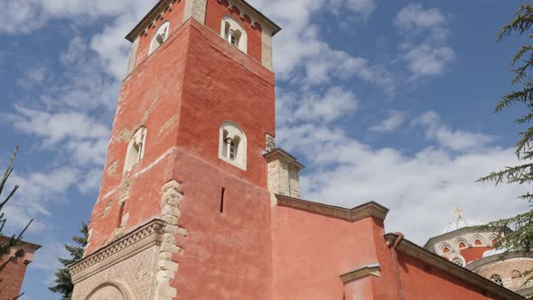 Red facade of old Serbian orthodox monastery Zica 4K tilting video