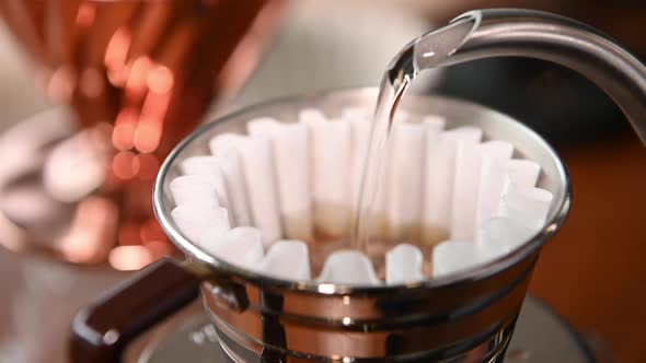 The barista is brewing coffee with traditional drip brewing equipment.