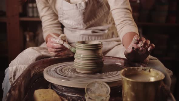 Young Woman Potter Working with a Wet Clay  Painting the Clay in Green Color with a Brush