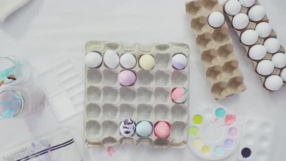 Flat lay. Little girl painting craft Easter eggs with acrylic paint.