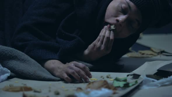 Person Giving Piece of Bread to Hungry Homeless Woman Lying on Ground, Poverty