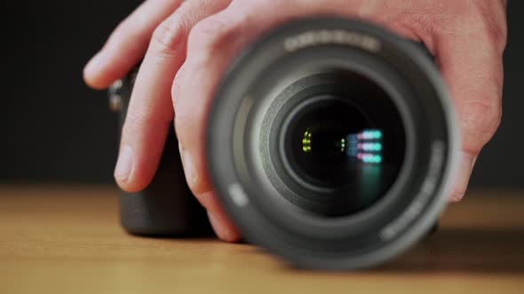 A caucasian man's hand zooming the camera lens in on wooden table