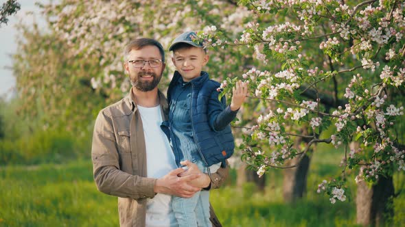 Portrait of a Happy Man with His Little Son in His Arms Standing in the Garden