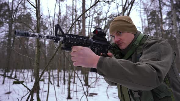 Serious Focused Military Man Aiming with Gun Walking in Winter Forest in Slow Motion