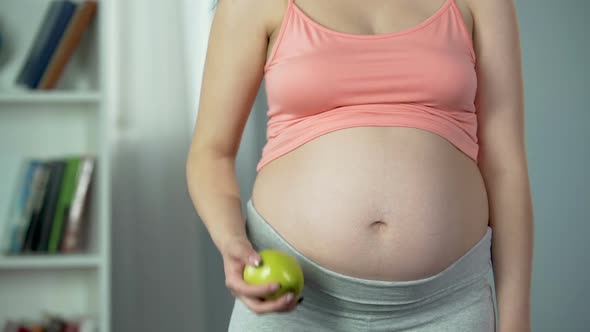 Pregnant Female Holding Out Fresh Green Apple, Enjoying Healthy Diet, Vitamins