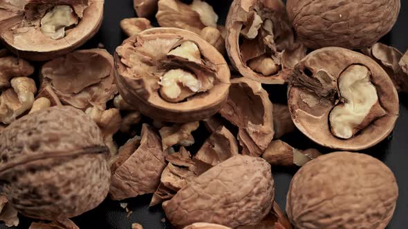 Lot of Walnuts in the Shell are Spinning on a Black Background