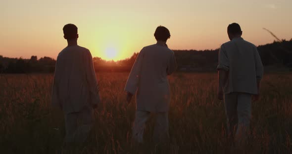 Young Guys are Walking in a Wheat Field