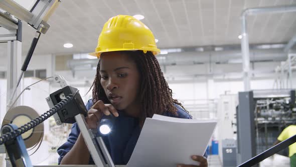 Female Engineer Holding Document and Checking Machine