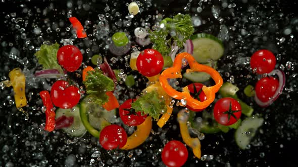 Super Slow Motion Shot of Flying Cuts of Colorful Vegetables and Water Drops on Black at 1000Fps