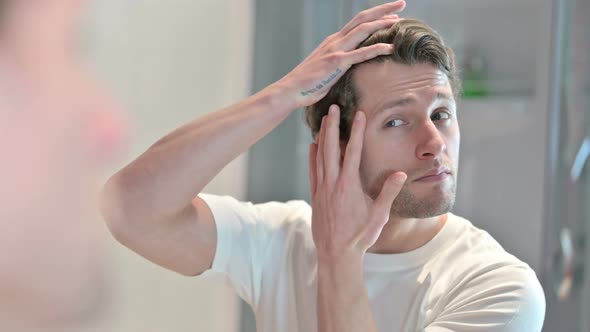 Rear View of Young Man Checking Forehead in Mirror