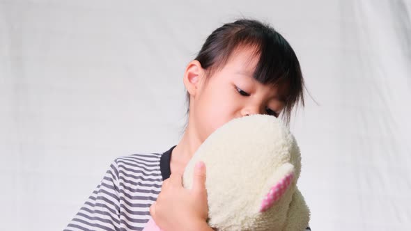 Cute little girl hugging and kissing doll on white background. alt