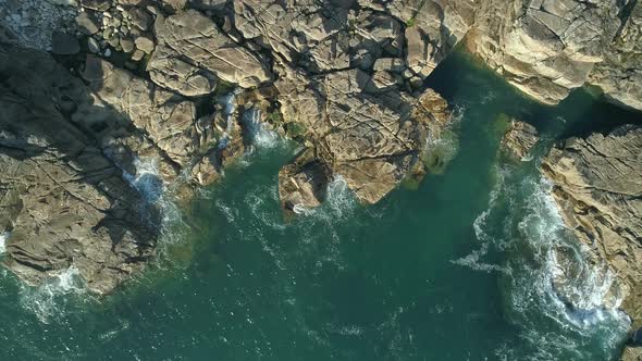 Top down aerial of the ocean lapping at rocky out crops