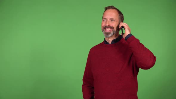 A Middleaged Handsome Caucasian Man Talks on a Smartphone with a Smile  Green Screen Background