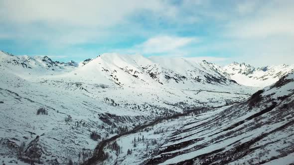 Flying in a winter valley with road and creek below.