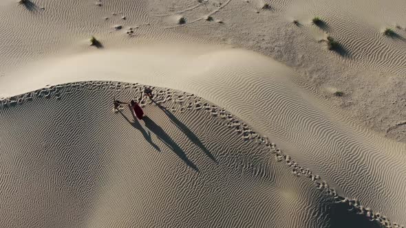 Top View on Three Women Dancing in the Middle of the Desert in the Morning