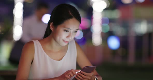 Woman sending audio message on cellphone at night