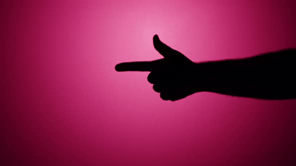 Shadow of Hand Showing Gun with Fingers on Pink Neon Background