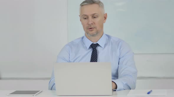 Tired Senior Businessman Yawning at Work