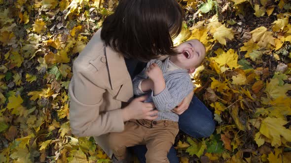 Joyful Mom Tickling Laughing Toddler Son in Park