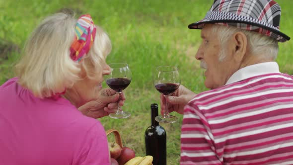 Family Weekend Picnic in Park. Active Senior Old Caucasian Couple Sit on Blanket and Drink Wine