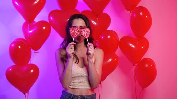 Cheerful Young Woman with Heart Shaped Lollipops