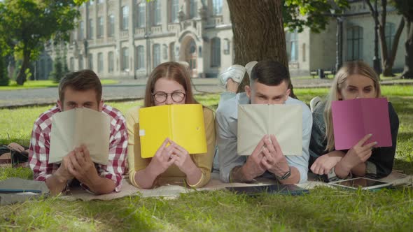 Four Cheerful Caucasian Students Putting Down Books and Smiling. Portrait of Young Boys and Girls