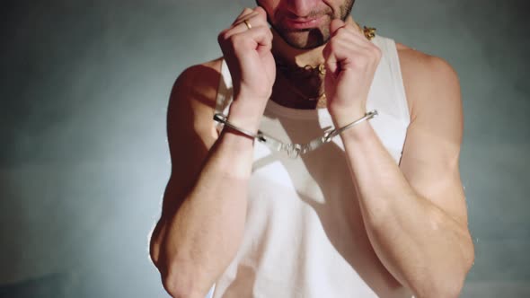 Gangster with Handcuffs on His Hands is Trying to Free Himself