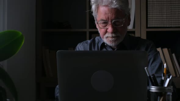 Senior man working on laptop, sitting at desk