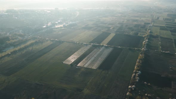 Aerial View of Agricultural Fields Near the City Suburb in the Morning at Sunrise