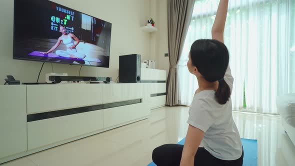 Asian beautiful young girl follow sport training video to exercise in house by watch online trainer.