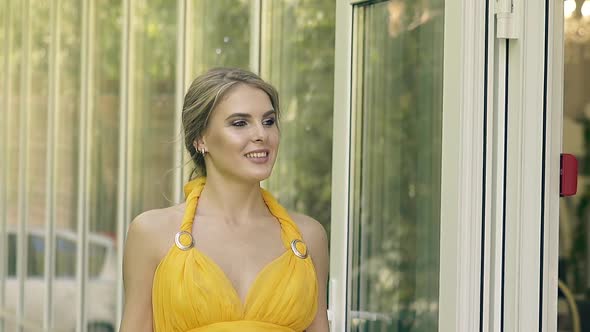 CU Slow Motion Young Beautiful Girl in a Lush Yellow Evening Gown Walks Along the Transparent