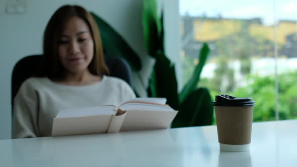Closeup of a young asian woman reading book and drinking coffee