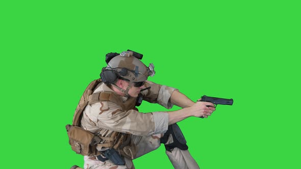 Soldier Is Shooting From Pistol Sitting on His Knee on a Green Screen, Chroma Key.