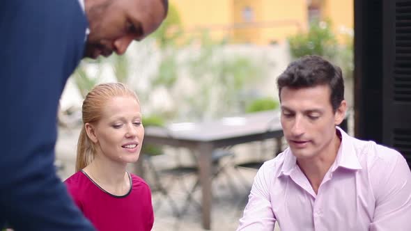 Colleagues having casual meeting outdoors, using laptop computer