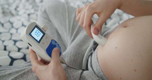 Young Pregnant Woman Using Pocket Ultrasound Doppler to Check Baby Heart Rate