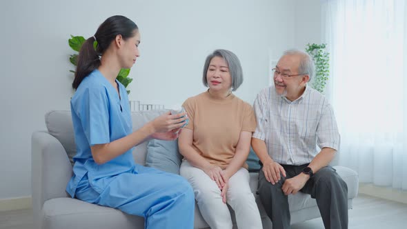 Asian senior older couple consult with caregiver woman at nursing home.