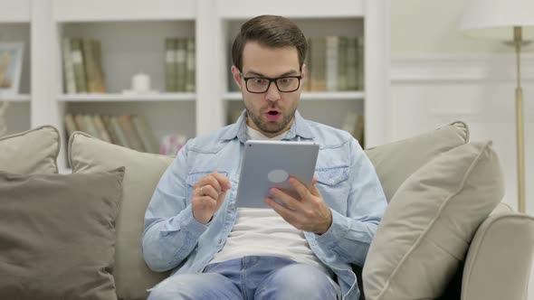 Young Man Celebrating on Tablet at Home