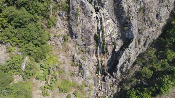 Majestic high waterfall from rocky cliff in Portugal, aerial orbit view