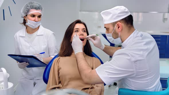 Stomatologist and Assistant Working As Team to Client Examining