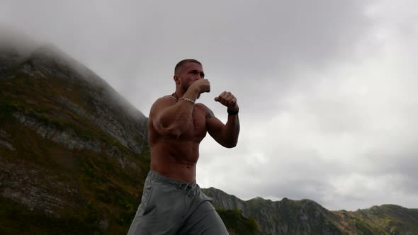 a Bearded Man with a Bare Muscular Torso is Boxing in the Mountains