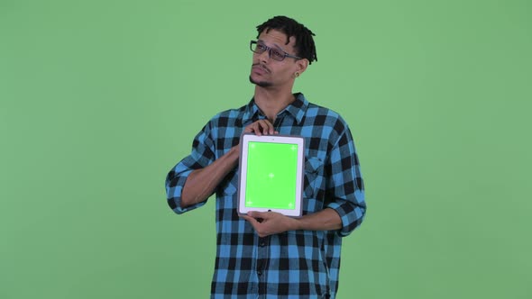 Happy Young African Hipster Man Thinking While Showing Digital Tablet