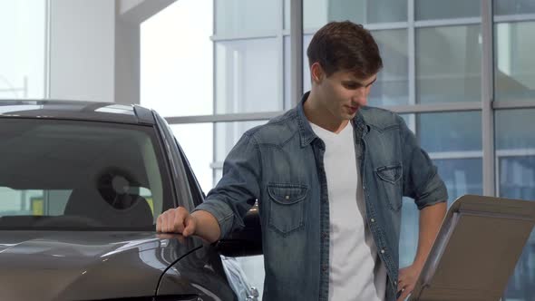 Man Reading Info Paper at Car Dealership Choosing New Auto