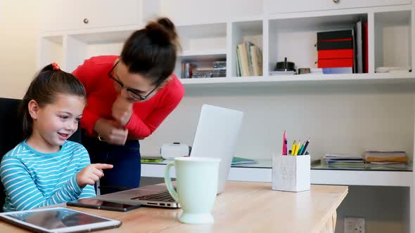 Mother assisting her daughter in using laptop 4k