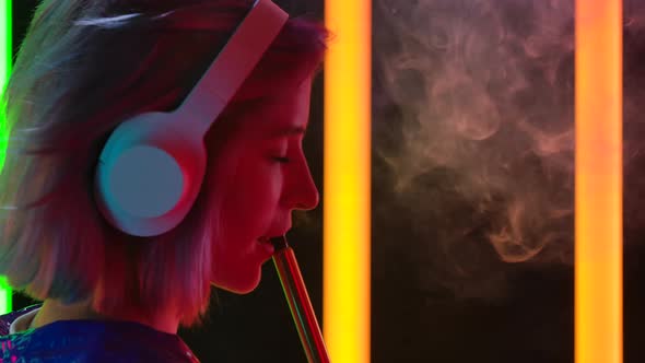 Portrait of a Young Stylish Woman Listens To Music in Big White Headphones, Dances and Smokes a