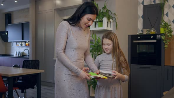 Caucasian Mother and Daughter in Similar Dresses Choosing Kitchen Color Standing in Shop Indoors