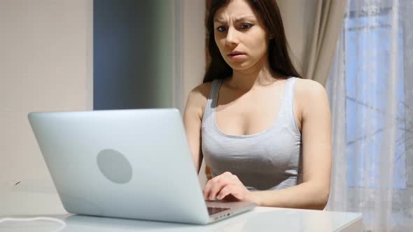 Young Woman Upset by Loss while Working on Laptop