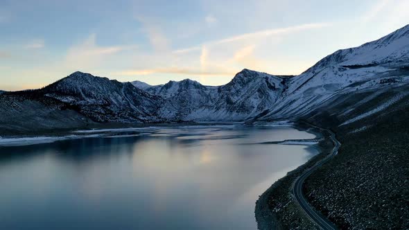 Lake reflection, coastal road and majestic snowy mountain range, aerial drone view