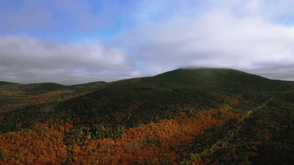 Aerial footage pulling back from mountain in peak autumn colors