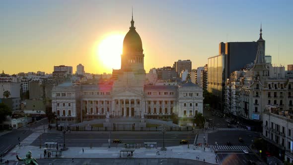 Aerial lowering on Congressional square with sun setting behind Argentine Congress building at golde